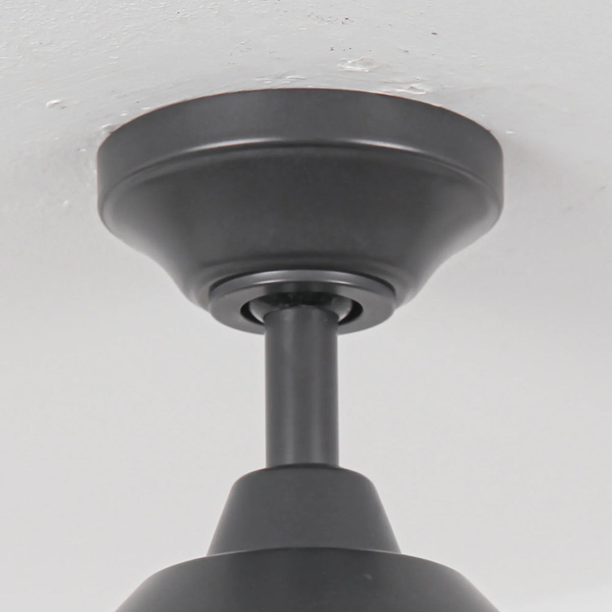 Close-up of a matte black ceiling fan mounting bracket and downrod