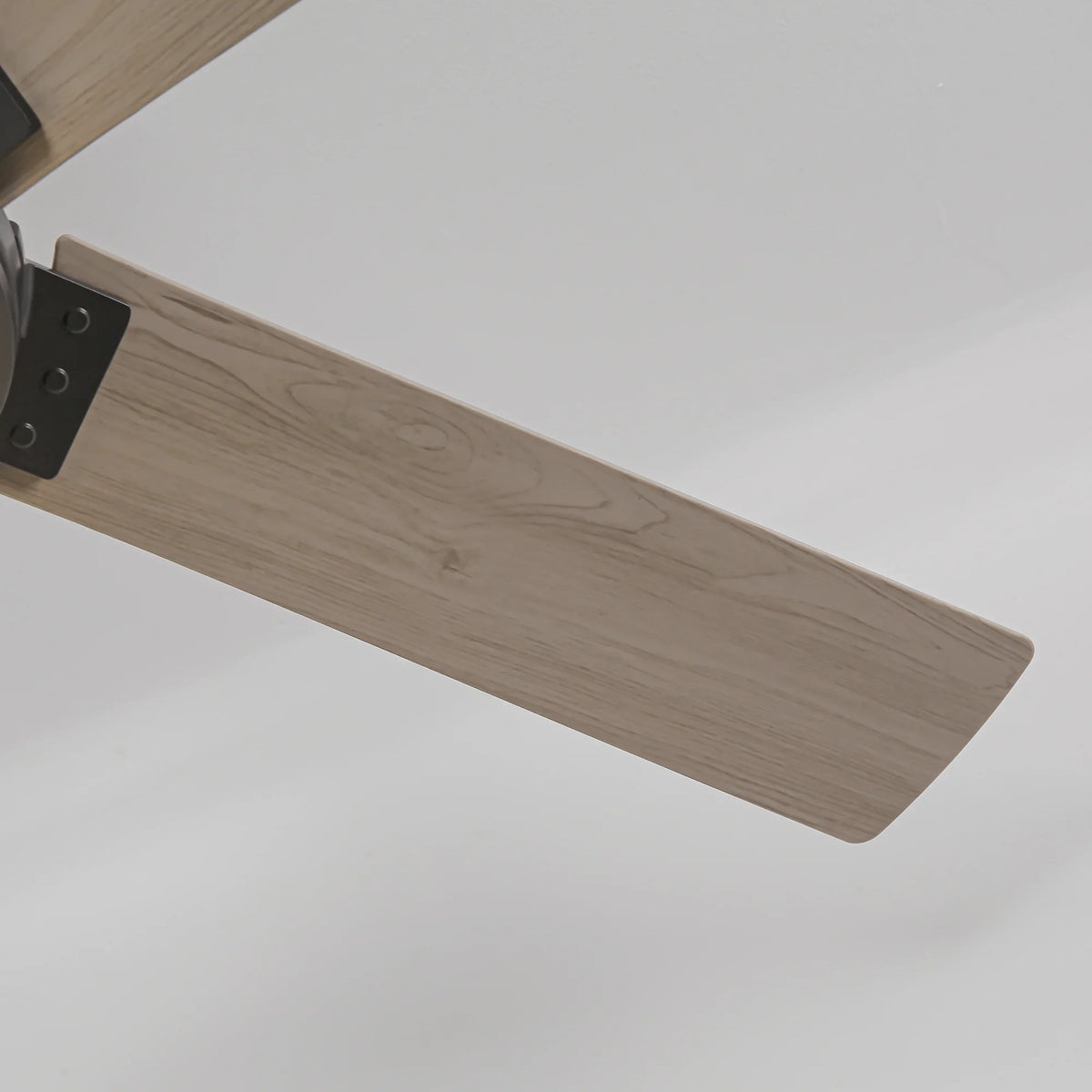 Close-up of a modern ceiling fan blade with a light wood grain finish.