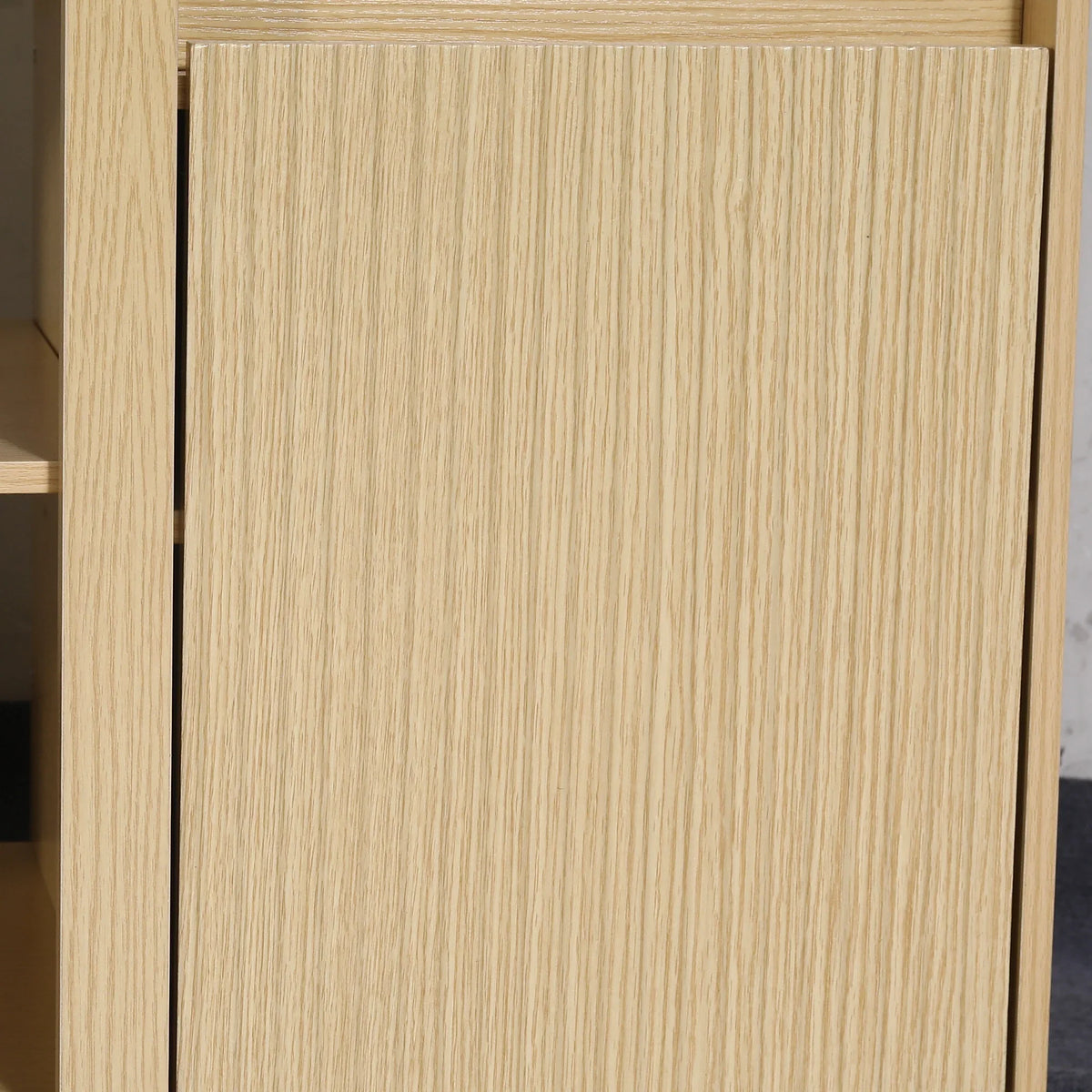 Close-up of a light-colored natural oak wood cabinet door with vertical grain.