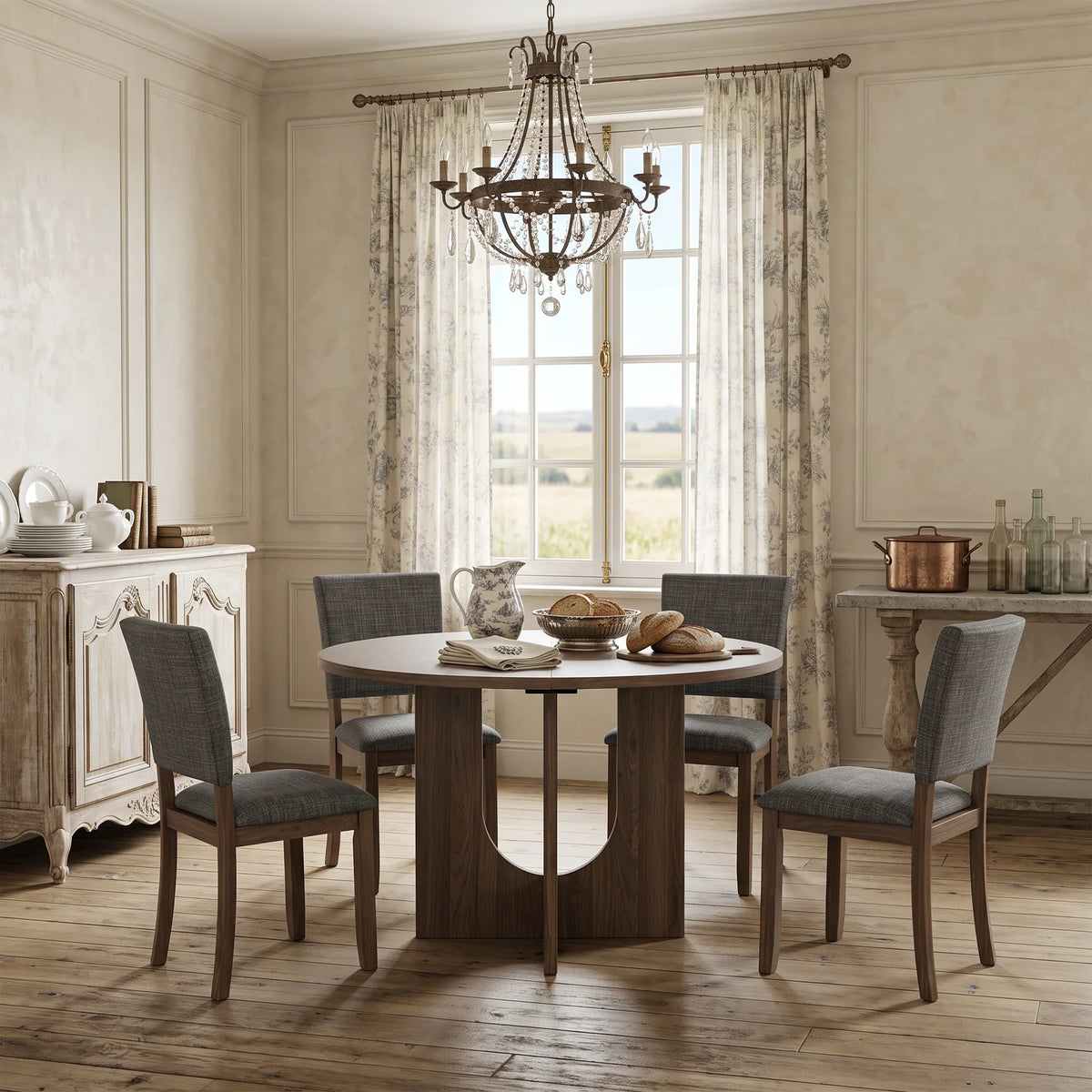 Elegant dining room featuring a round wooden table, gray upholstered chairs, and a crystal chandelier.