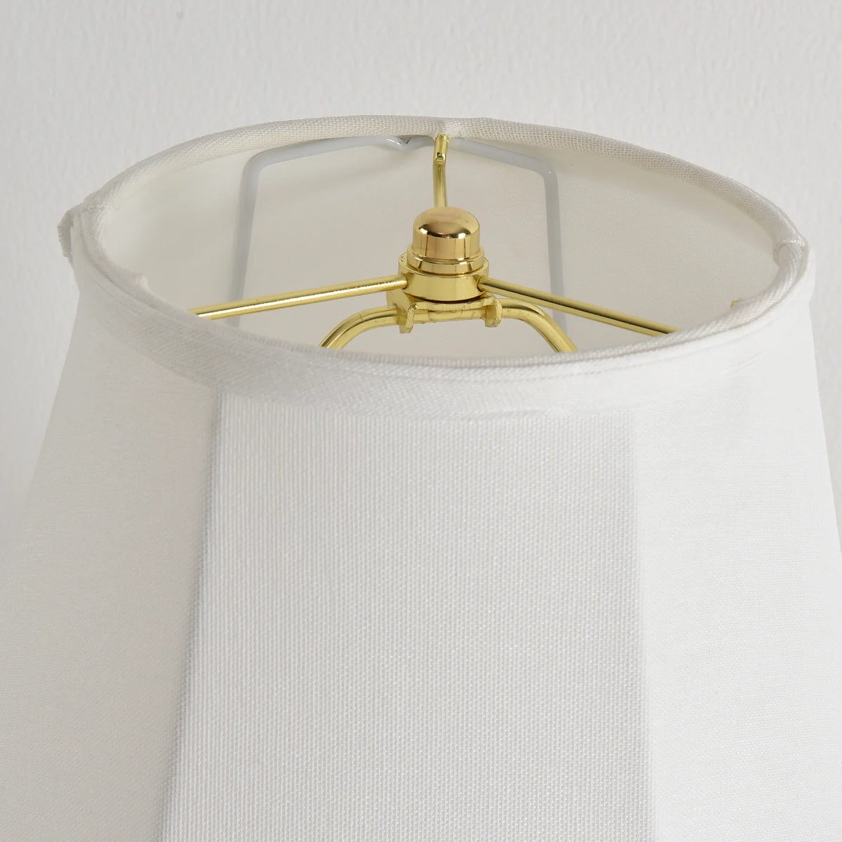 Interior view of a white lampshade showing the gold-toned metal frame and harp.