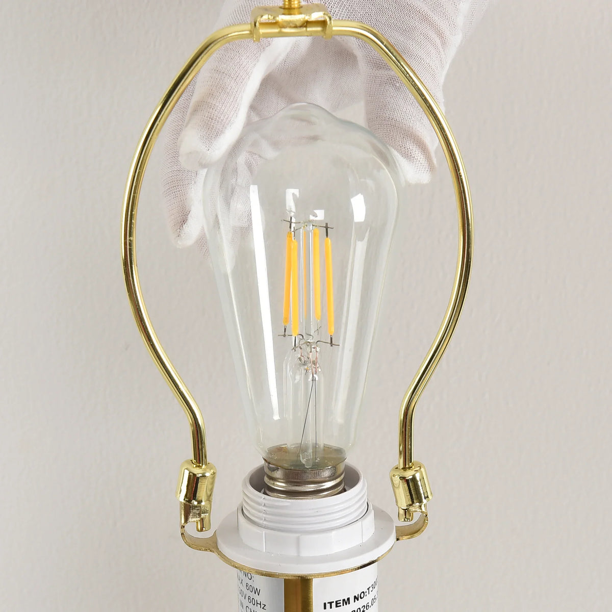 Close-up of a vintage-style LED filament bulb installed in a gold light fixture socket