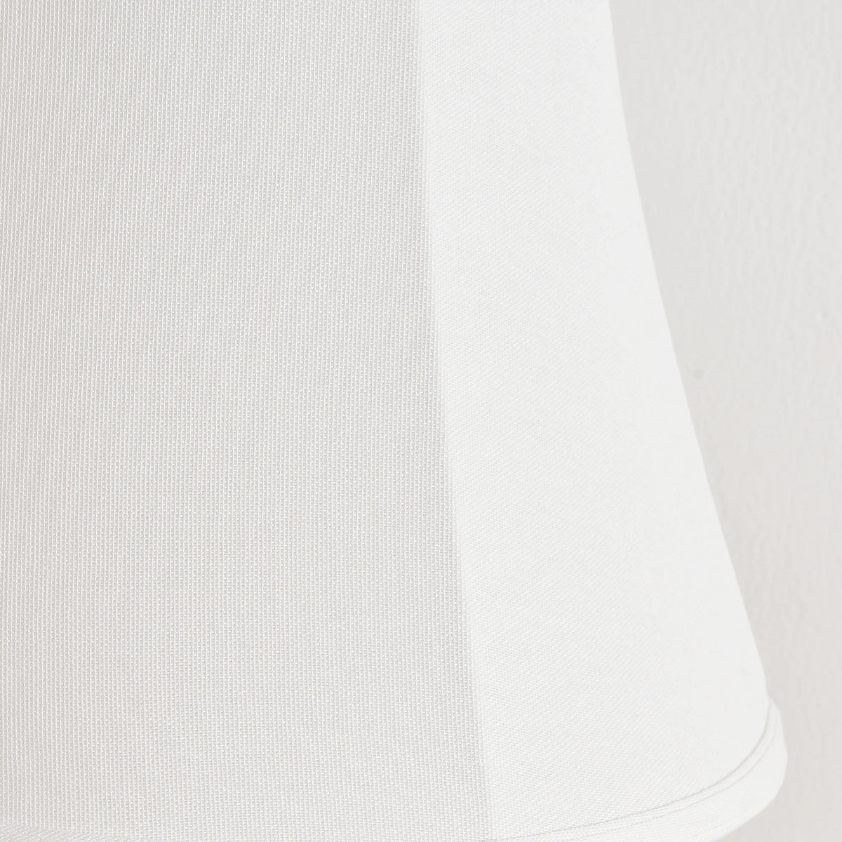 Close-up of a white fabric lampshade with a subtle textured weave