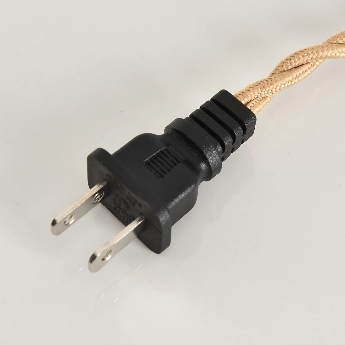Close-up of a black two-prong power plug with a braided tan fabric cord