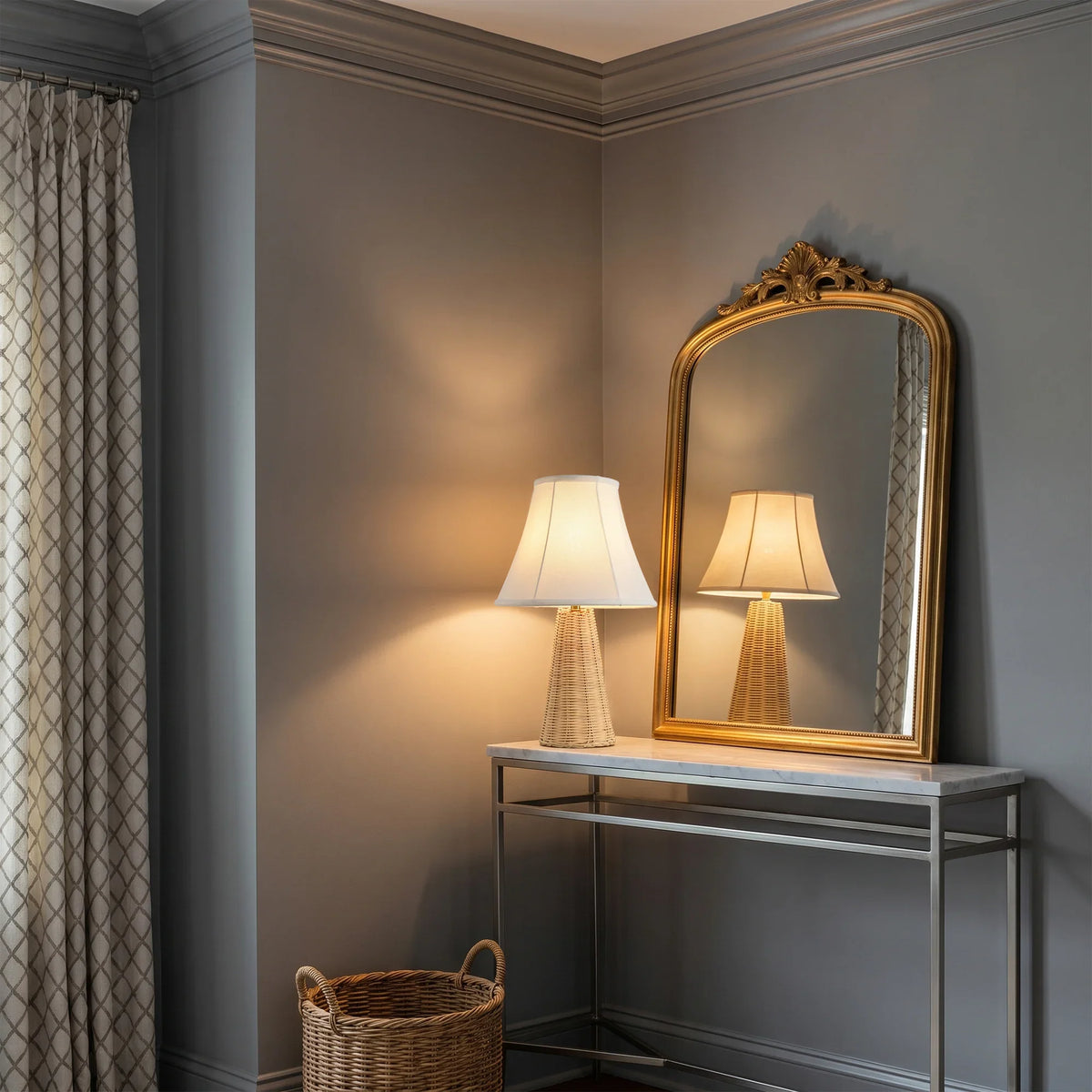 Elegant gold-framed mirror and table lamp on a modern console table in a grey room.