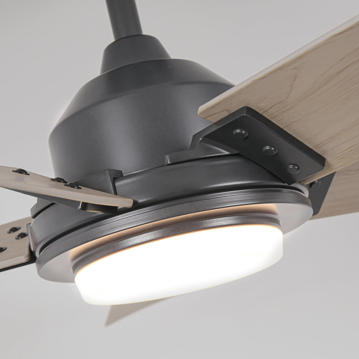 Close-up of a modern matte black ceiling fan with light wood blades and an integrated light.